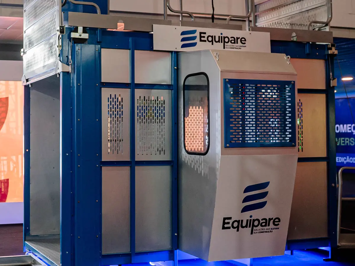Elevador cremalheira Equipare: cabine com visor do operador, painel de comando e mastro azul, com a marca aplicada